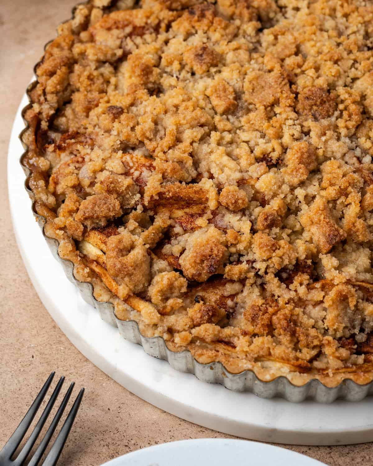 Close up of a baked apple crumble tart in a tart pan.