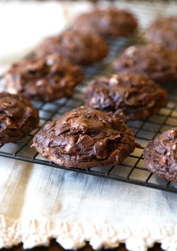 Chocolate cookies with white chocolate chips cooling on a wire rack.