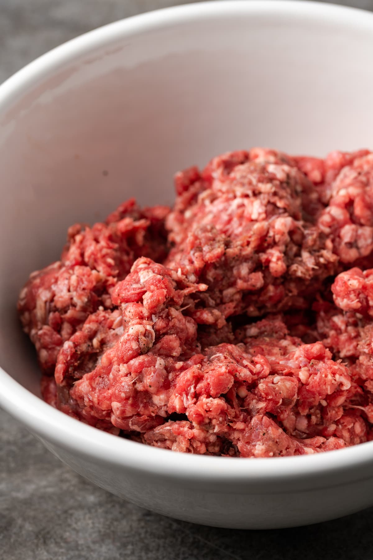 Ground beef in a white mixing bowl.