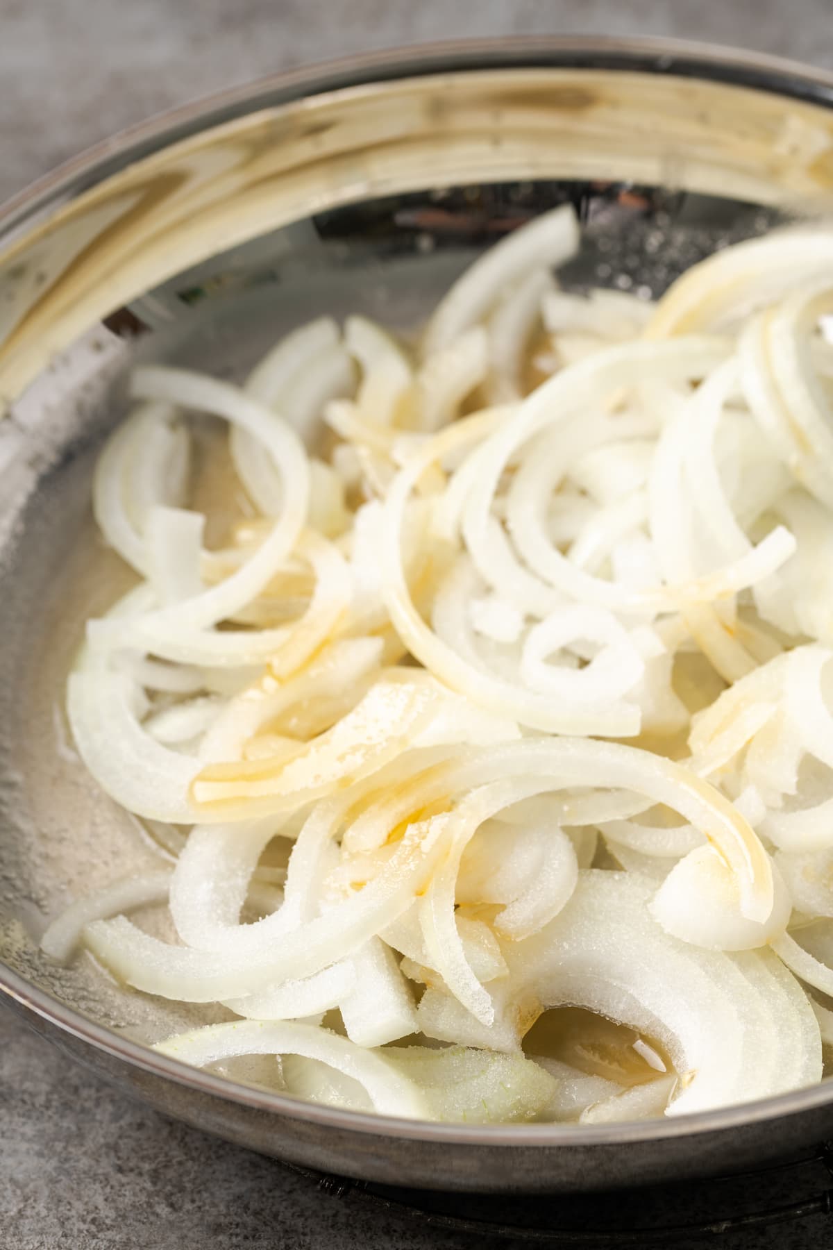 Uncooked onion slices added to a skillet.