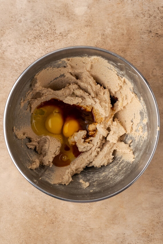 Eggs and vanilla added to creamed butter and sugar in a mixing bowl.