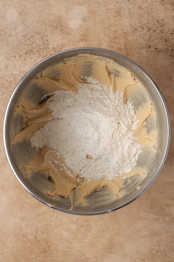 Dry ingredients added to wet cinnamon bread batter in a mixing bowl.