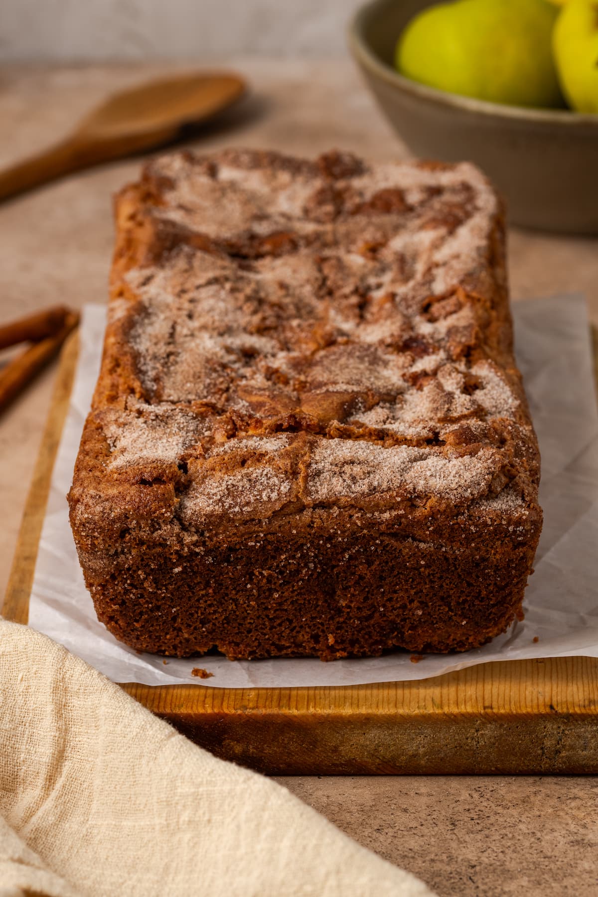 A loaf of apple cinnamon bread on a parchment-lined cutting board.