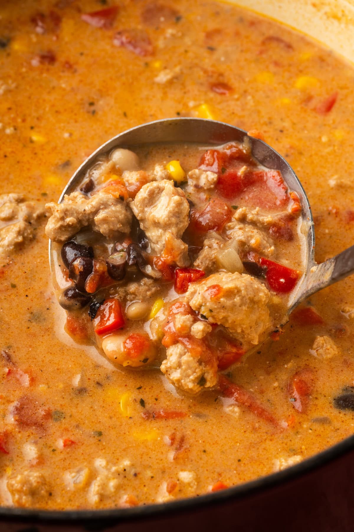 A ladle scooping creamy taco soup from a large pot.