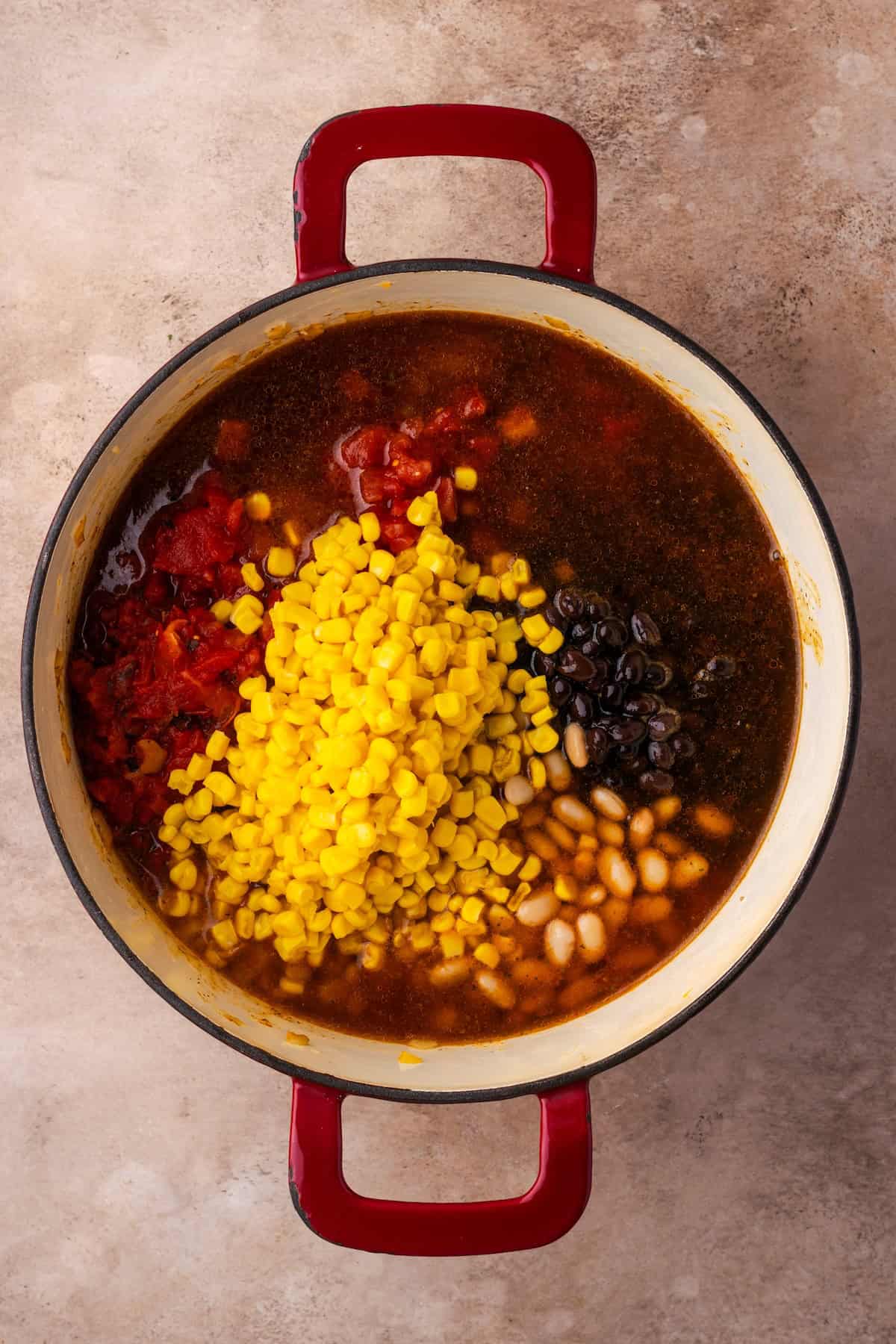 Corn and beans added to a pot of taco soup.