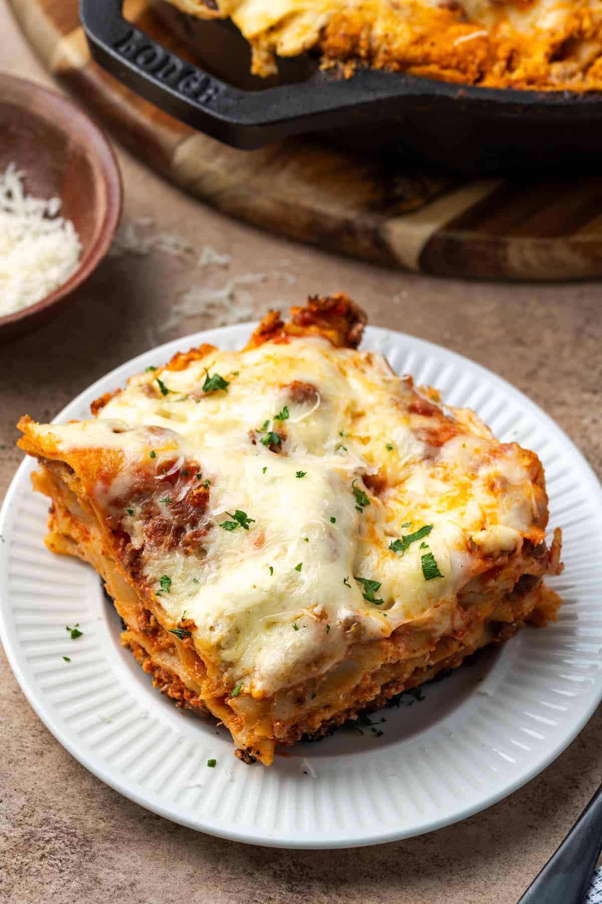 Close up of a slice of skillet lasagna on a white plate.
