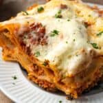 Close up of a slice of skillet lasagna on a white plate.