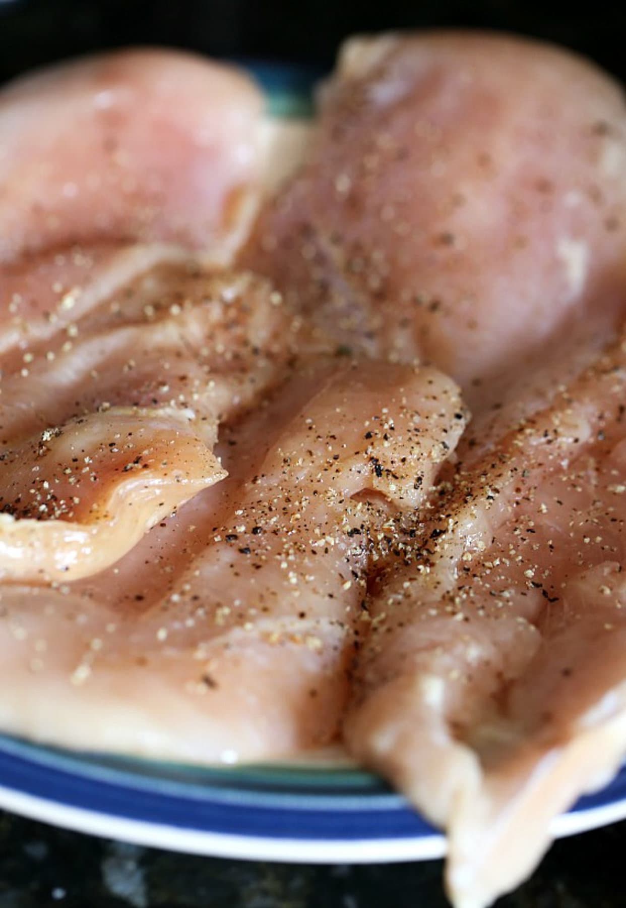 Raw chicken topped with salt and pepper 