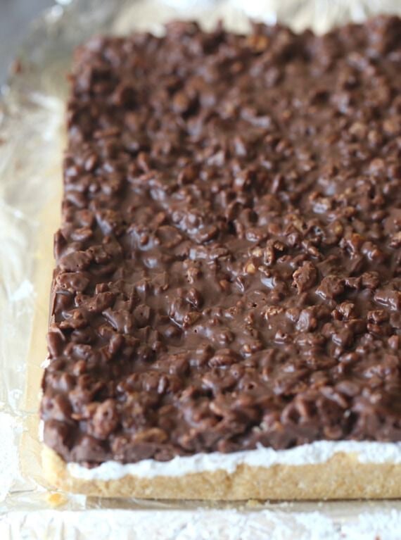 These s’mores bars layer a buttery Ritz cracker crust with gooey marshmallows and a chocolatey Rice Krispies treat topping. No oven required! Homemade s'mores cookie bars removed from the pan, ready to be cut into squares.