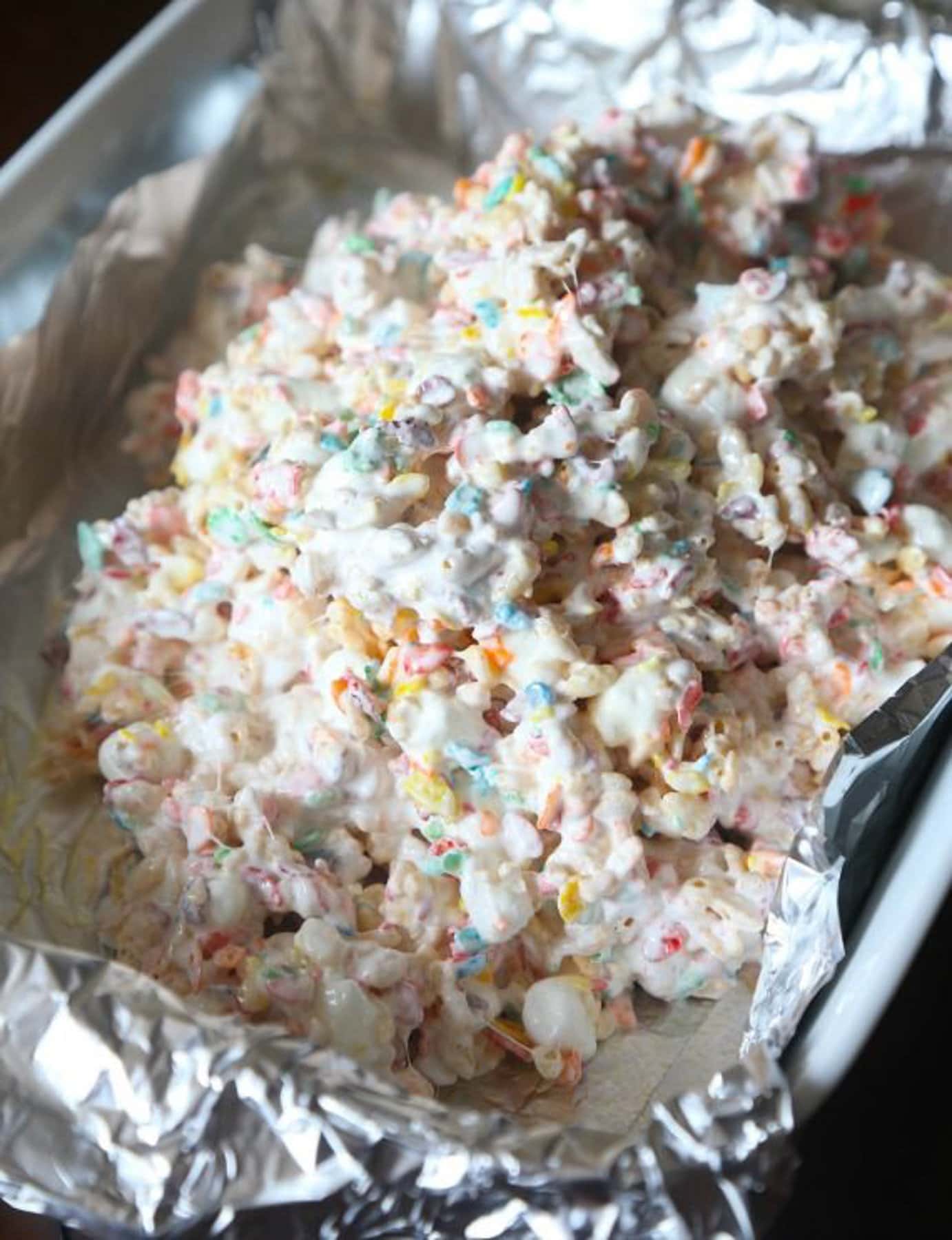 Krispie Treats made with Fluff and mini marshmallows being spread into a foil-lined pan