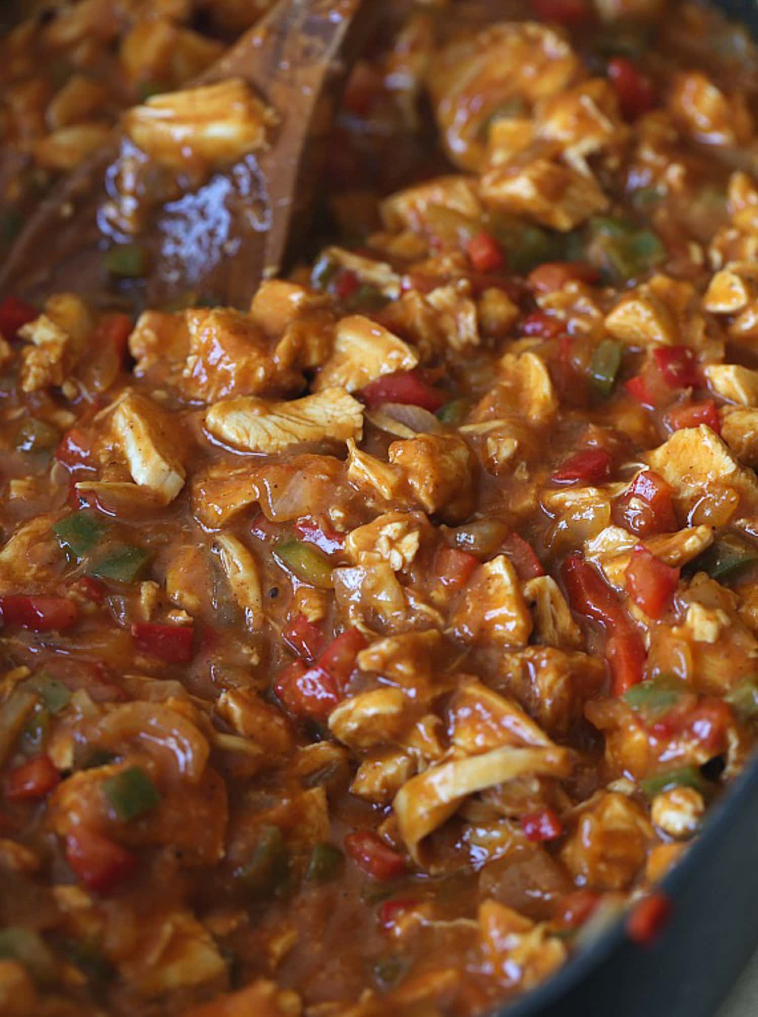 Red Enchilada sauce in a deep skillet with chicken added in.