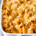 Baked Chicken Enchilada Pasta topped with melted cheese in a 9x13 white baking dish