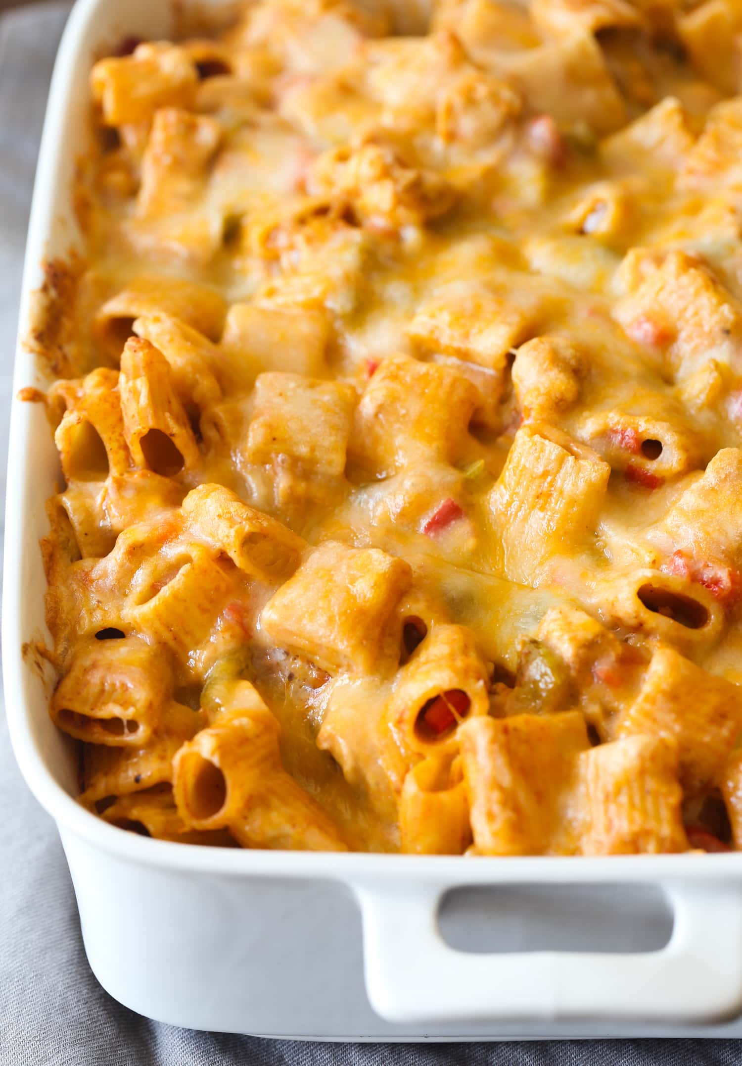 Baked Chicken Enchilada Pasta topped with melted cheese in a 9x13 white baking dish