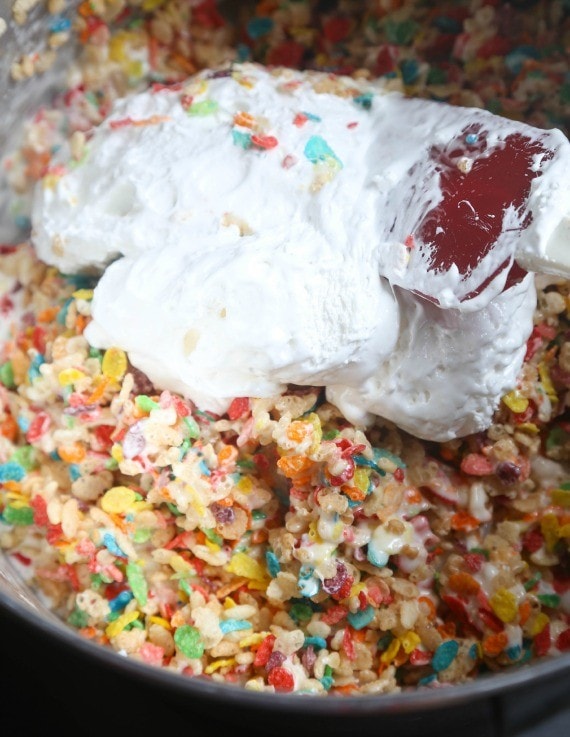 Fluff being added to a bowl of Krispie Treats mixture