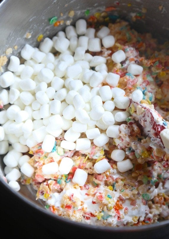 Mini marshmallows being added to a bowl of Krispie Treats mixture
