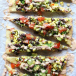 Overhead view Cowboy Caviar Pizza slices lined up on parchment paper