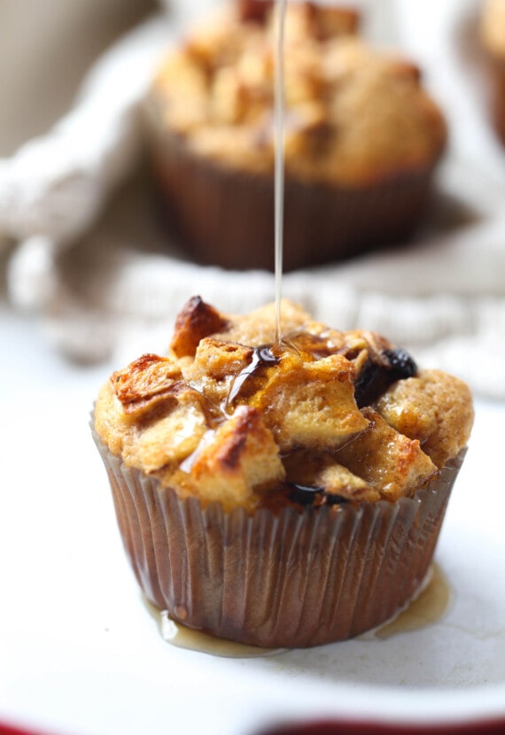 Maple syrup being drizzled on top of a French toast muffin served on a white plate.