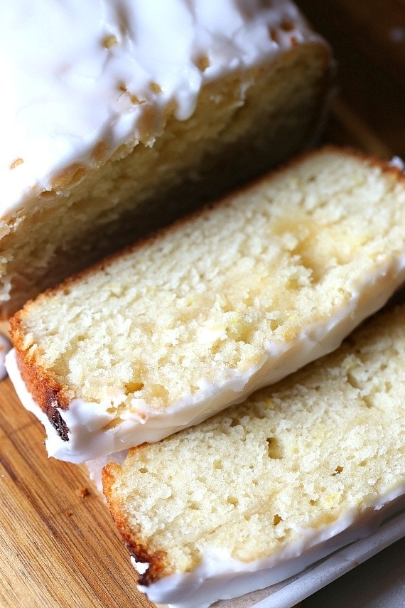 An overhead view of a glazed lemon curd cake cut into slices.