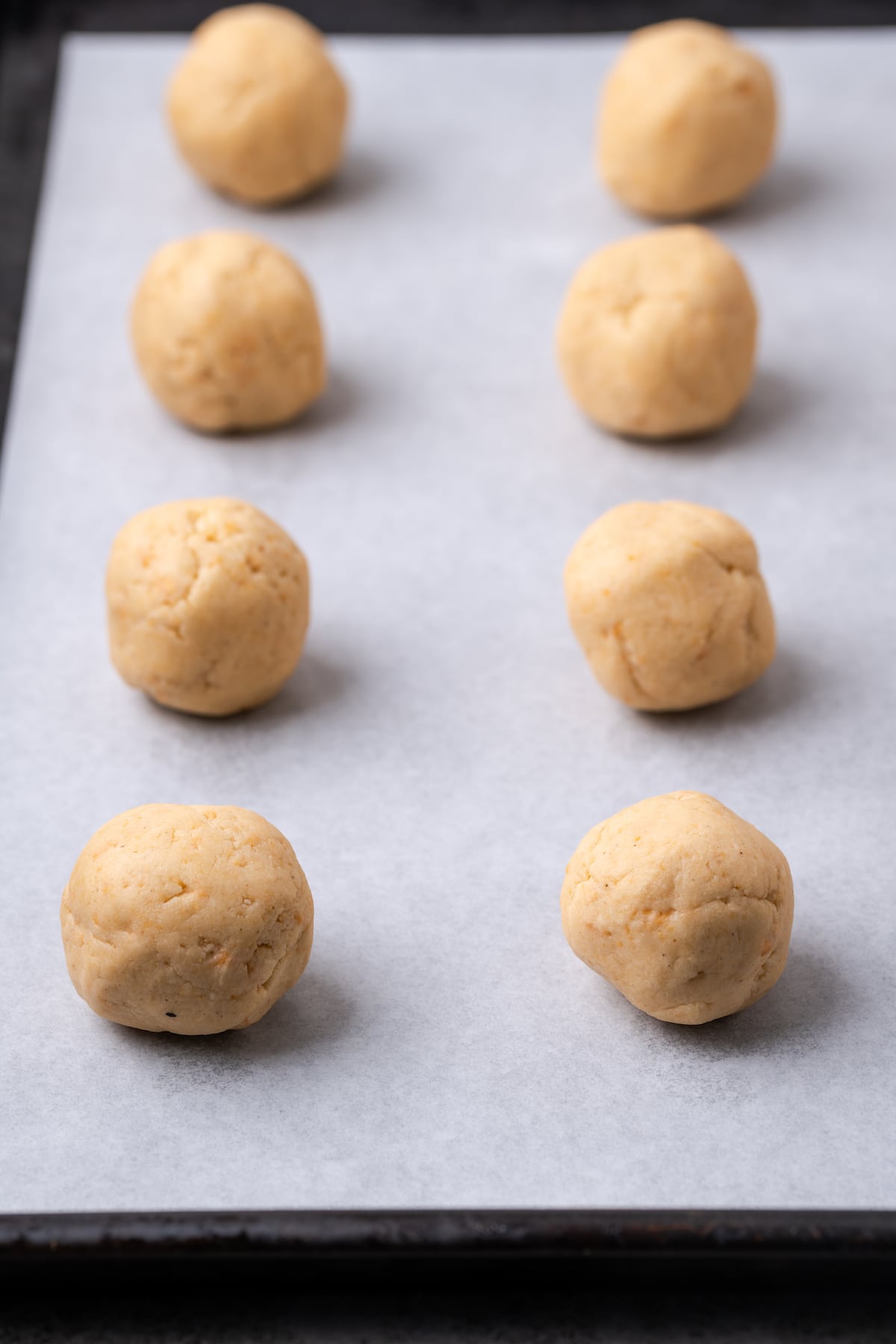 Butter pecan cookie dough balls on a lined baking sheet.