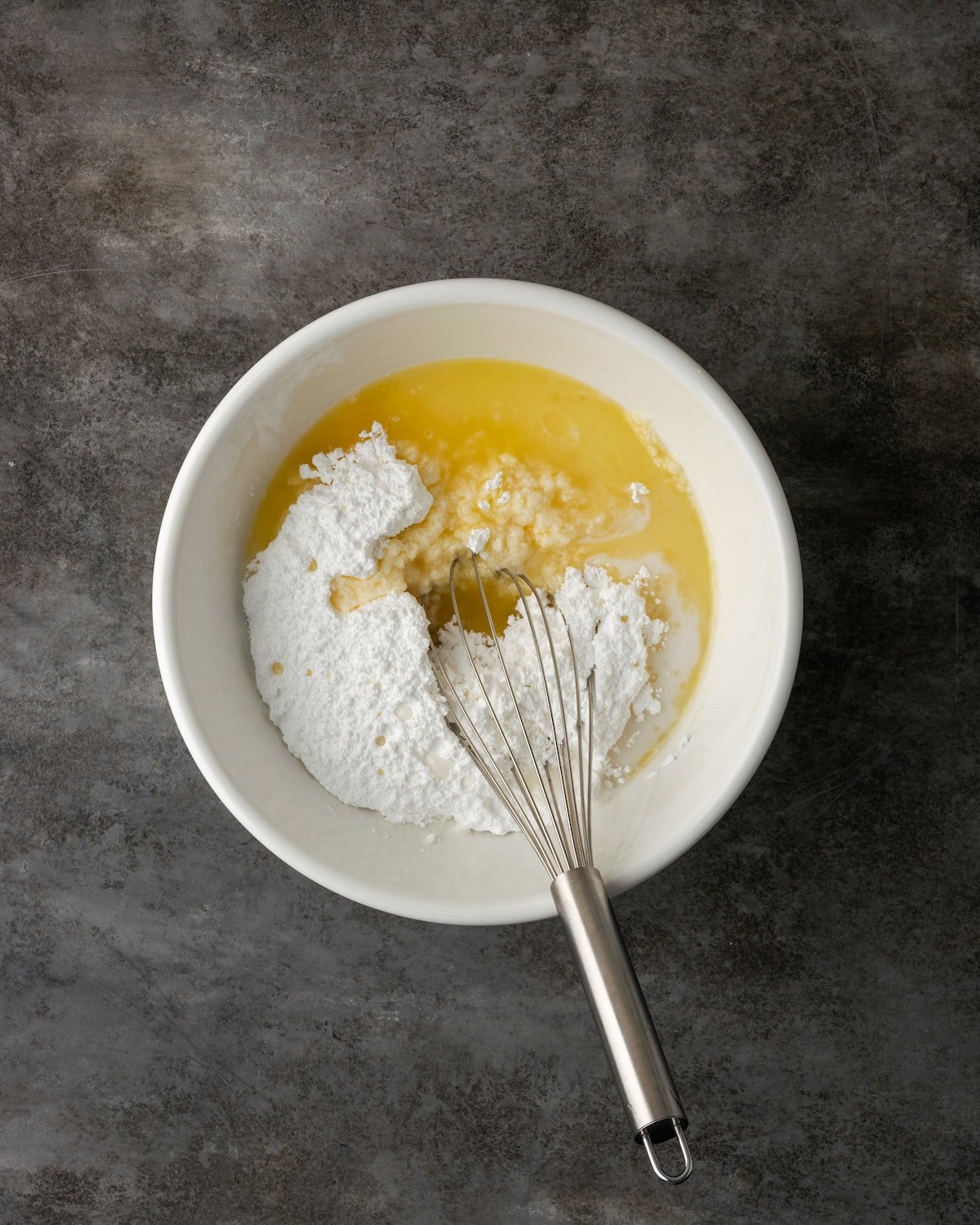 Frosting ingredients combined in a mixing bowl with a whisk.