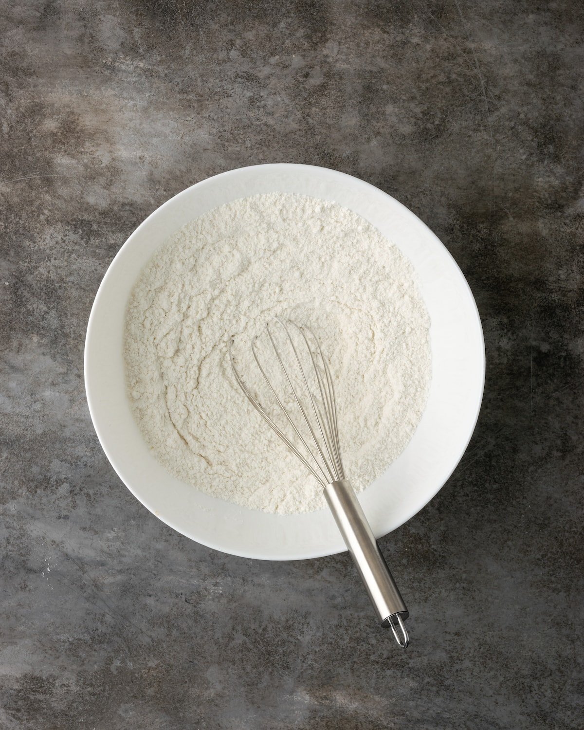 Dry cake batter ingredients whisked together in a mixing bowl.