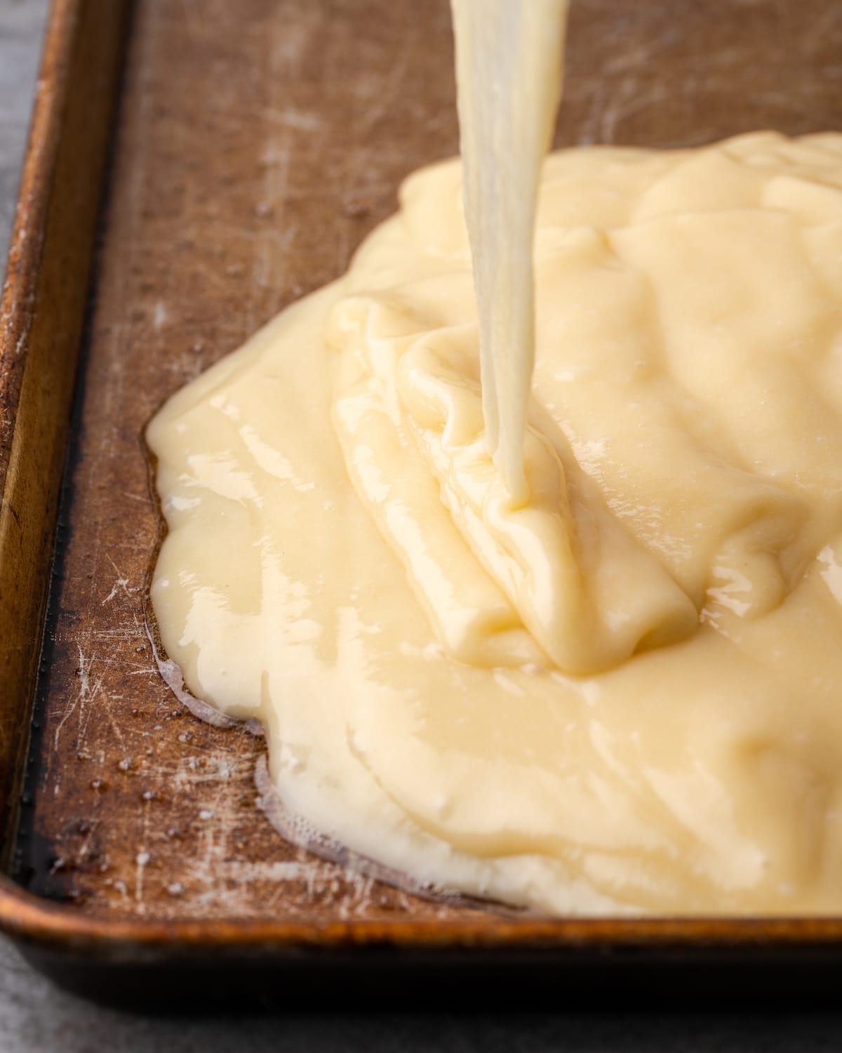 Buttermilk cake batter is poured into a greased metal sheet pan.