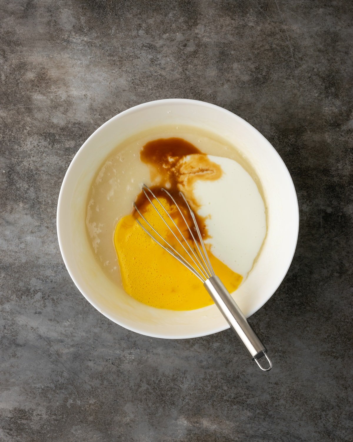 Eggs, vanilla, and buttermilk are added into a mixing bowl with dry batter ingredients.