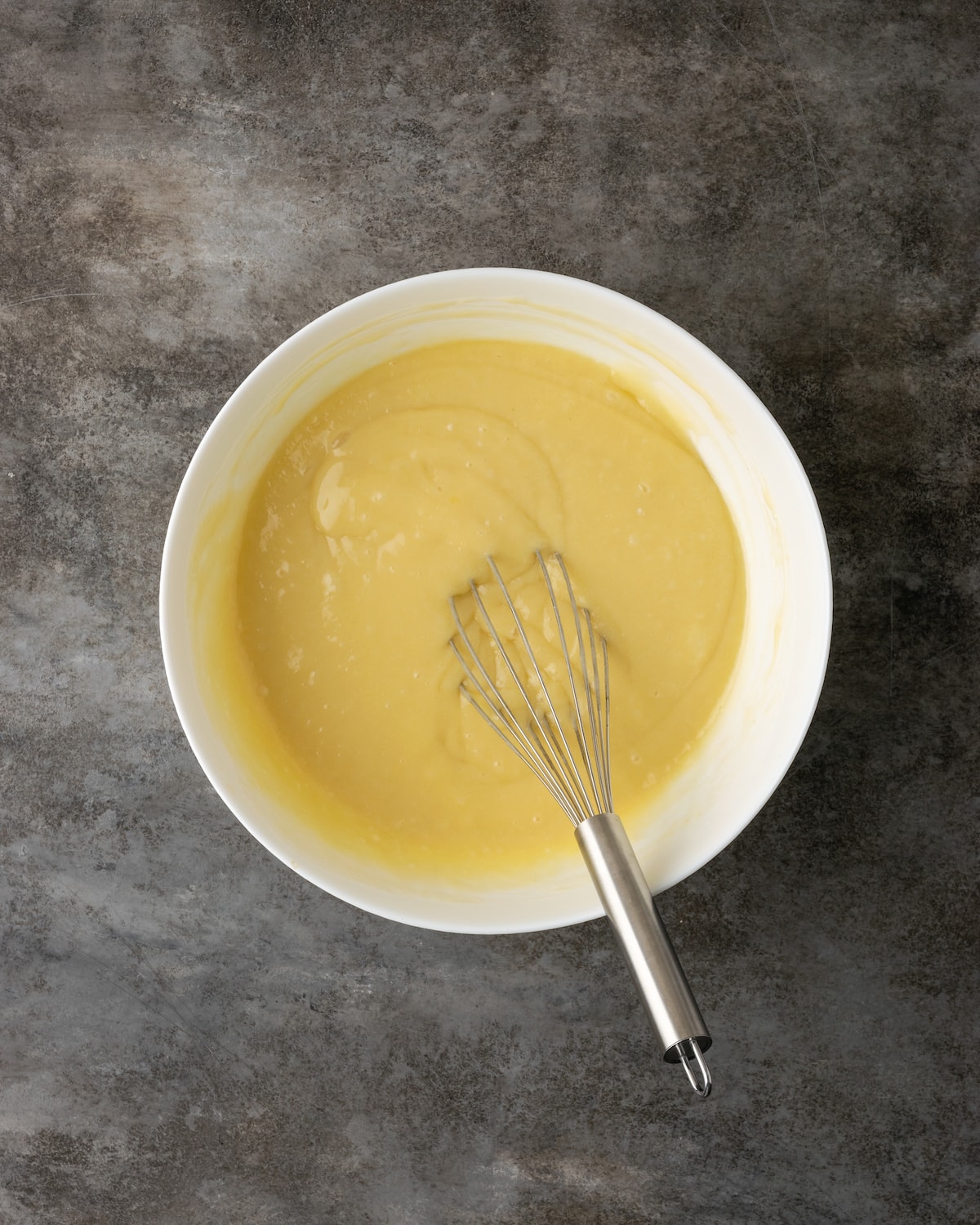 Buttermilk cake batter in a mixing bowl with a whisk.