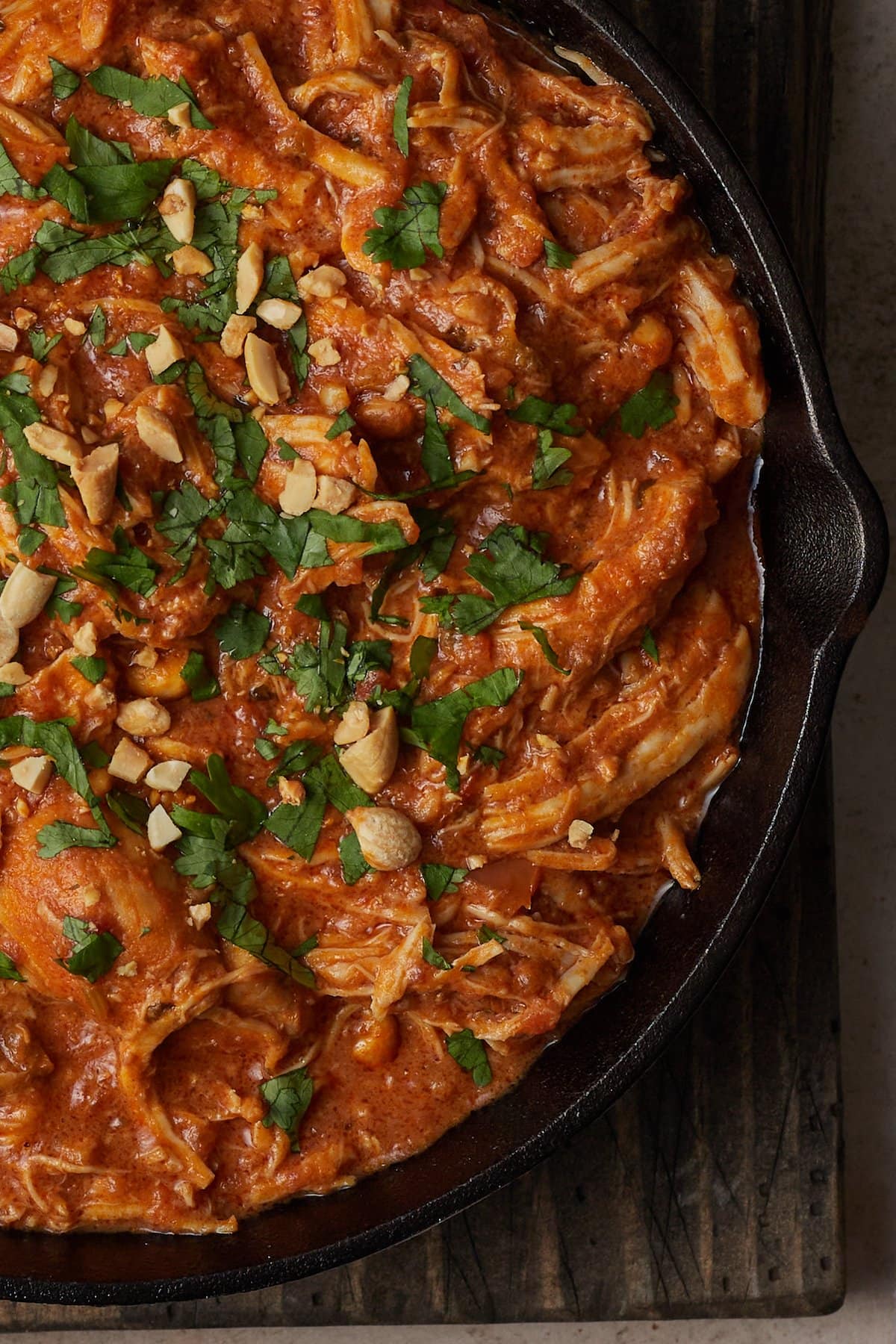 Top view of Slow Cooker Thai-Style Chicken served in a skillet, topped with cilantro and crushed peanuts.