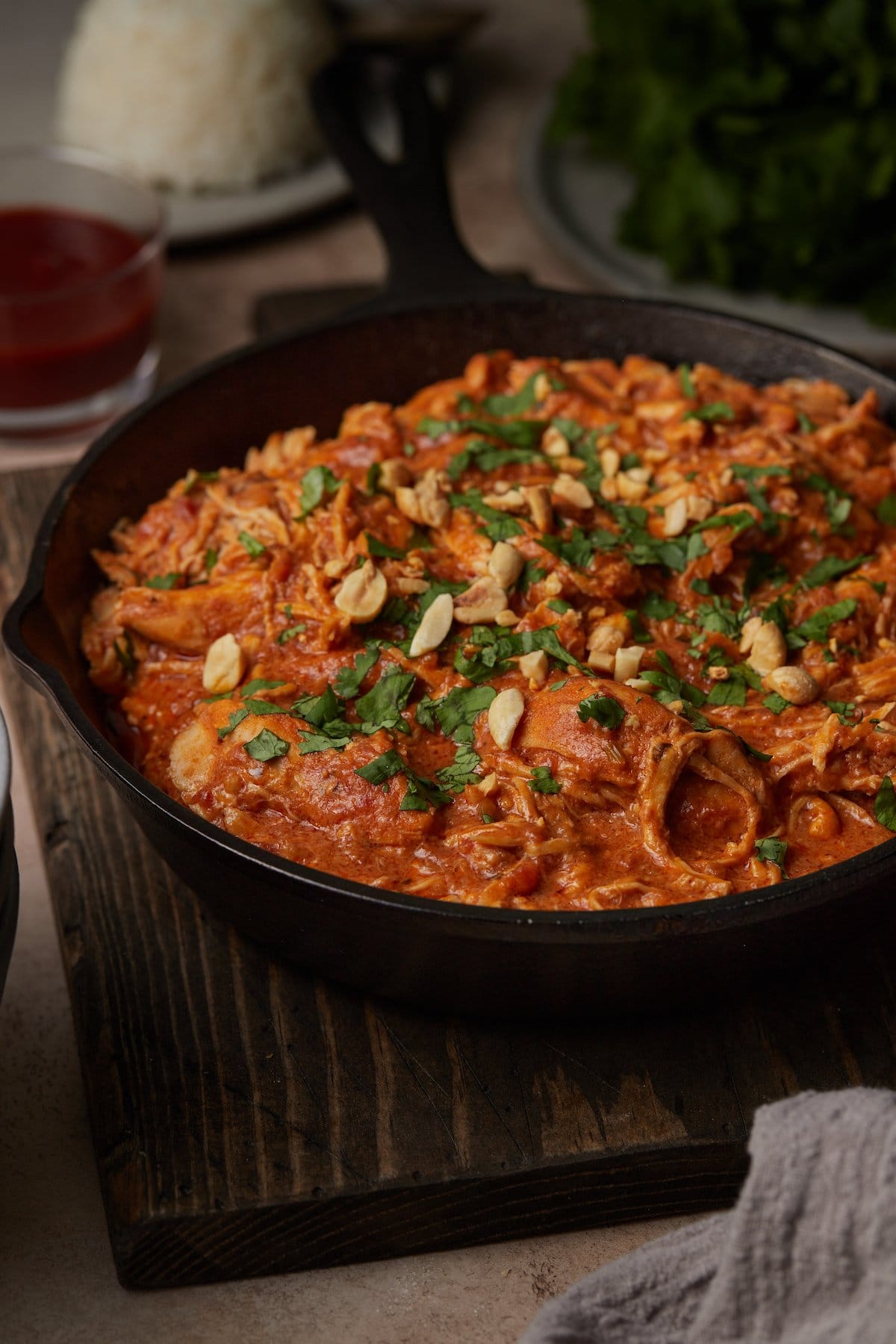 Slow Cooker Thai-Style Chicken served in a skillet, topped with cilantro and crushed peanuts.