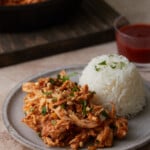 Slow cooker Thai-style chicken on a plate next to rice.