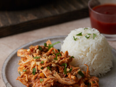 Slow cooker Thai-style chicken on a plate next to rice.