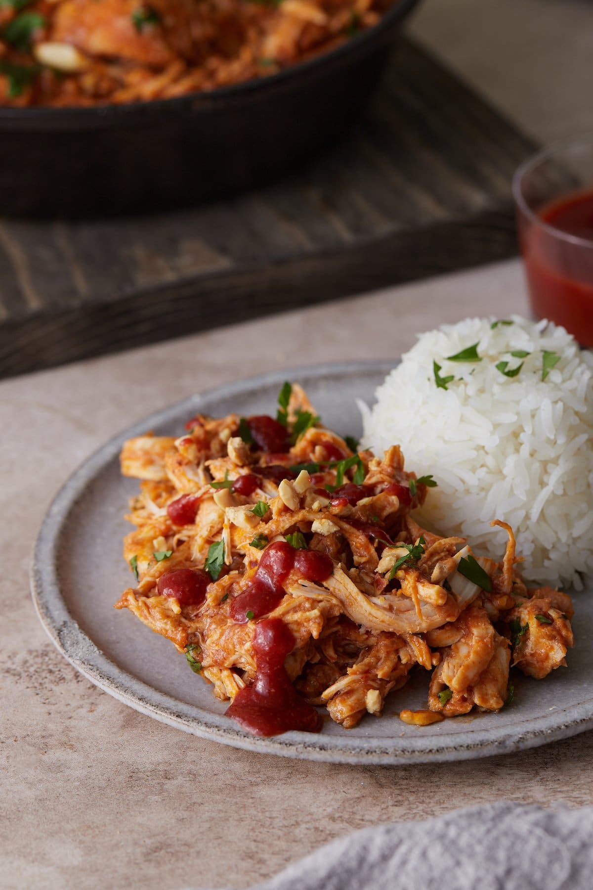 Slow cooker Thai-style chicken on a plate next to rice.