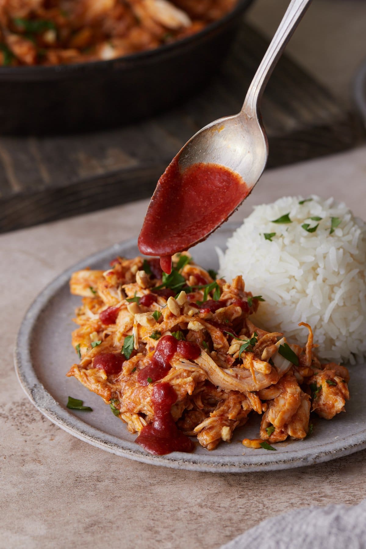 Hot sauce is drizzled over a plate of Thai-style slow cooker chicken.