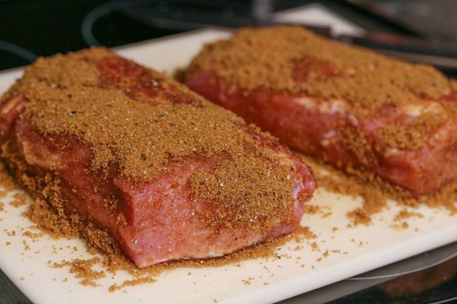 Top the pork roast with dry rub on a white cutting board