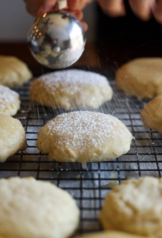 A Kentucky Butter Cake cookie on a cooling rack dusting them lightly with powdered sugar.