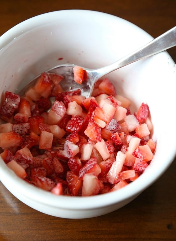 Quick and easy strawberry cinnamon rolls are soft, gooey, and loaded with fresh strawberries rolled inside refrigerated crescent roll dough. Chopped strawberries tossed with cornstarch in a bowl.