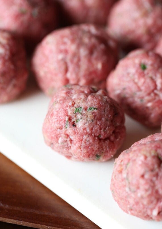 Raw meatballs on a plastic cutting board.