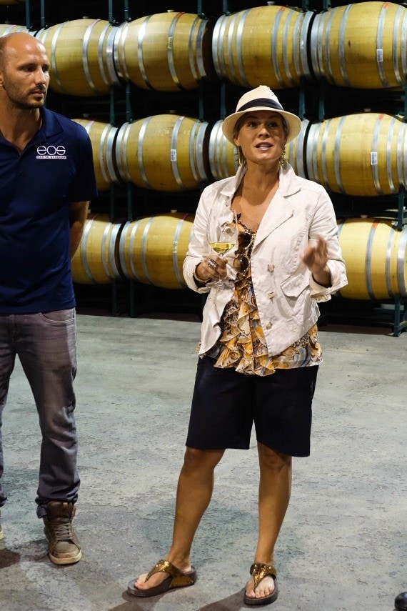 Cat Cora speaking in front of a bunch of barrels of aging wine