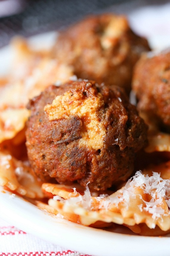 Close up of slow cooker ricotta stuffed meatballs served over pasta.