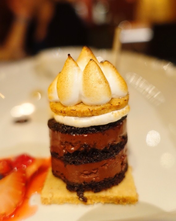 A "s'mores stack" dessert with torched marshmallow on top and juicy strawberries on the side