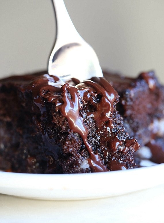 A fork stuck into a slice of chocolate earthquake cake on a plate.
