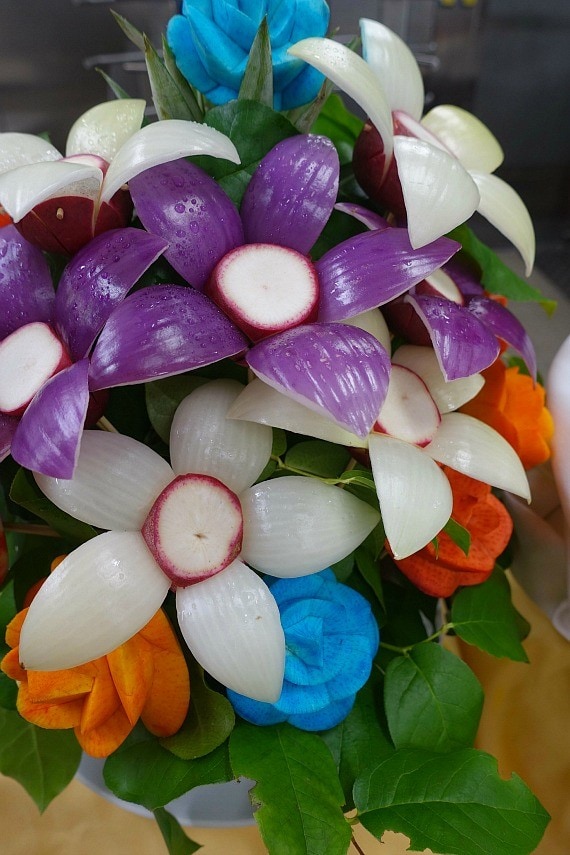 A floral designed centerpiece composed of onions and other raw veggies