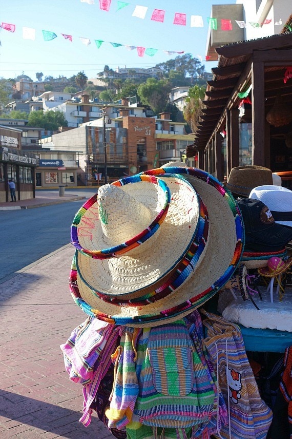 Three sombreros hanging with a bunch of handmade backpacks on the streets of Ensenada