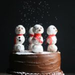 Chocolate frosted cake with snowman decorations on top