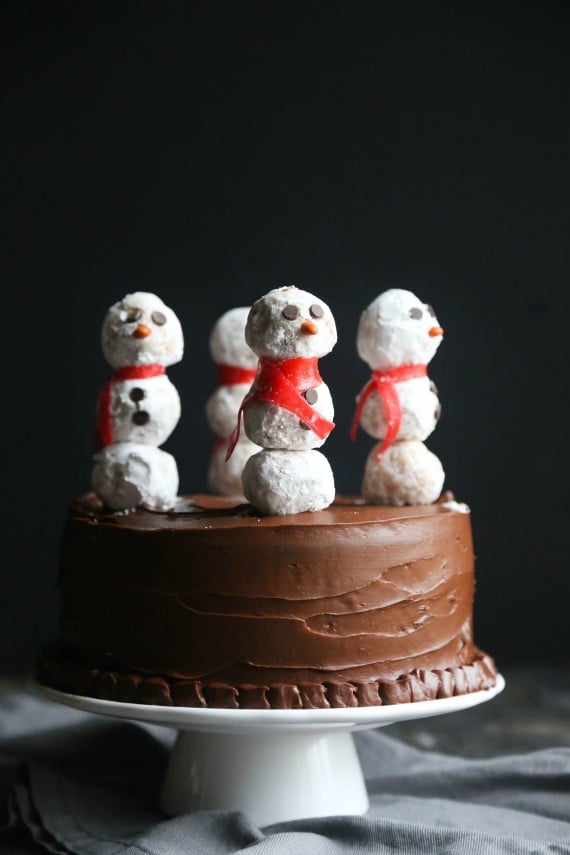 This gorgeous Snowman Cake is as simple to make as it is stunning! Donut Holes create adorable snowmen on sticks simply placed in the top of a chocolate cake!