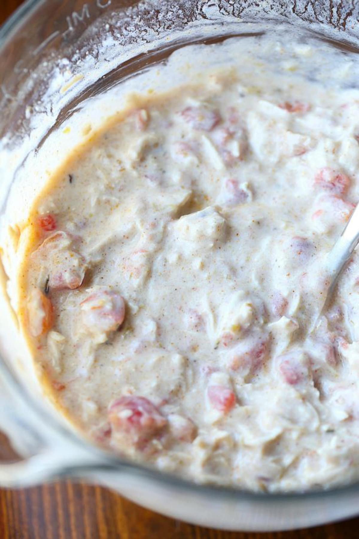 Salsa verde chicken combined with the casserole filling ingredients in a glass mixing bowl.