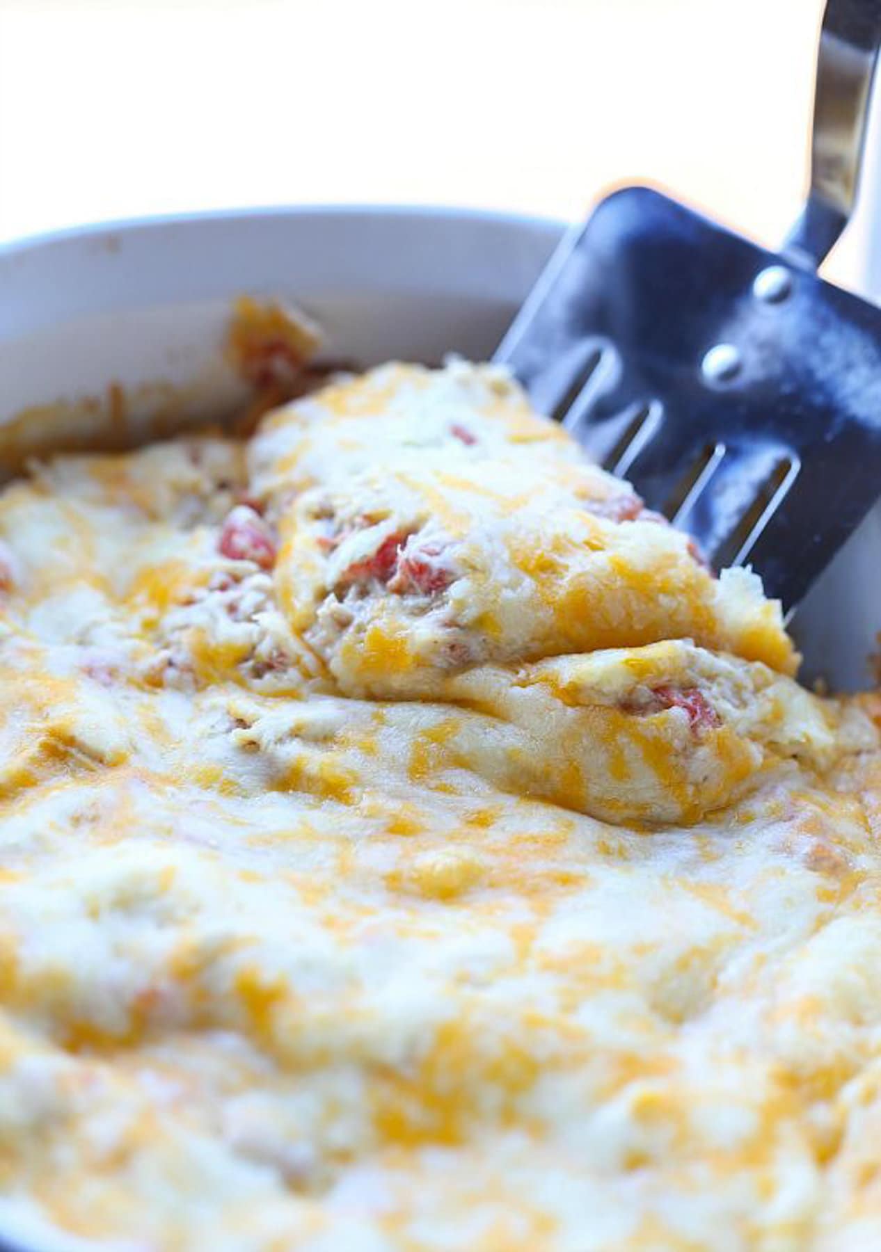 A spatula is used to scoop up a slice of salsa verde chicken casserole.