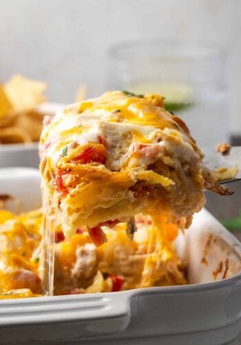 A serving of salsa verde chicken casserole being lifted from a baking dish with a spatula.