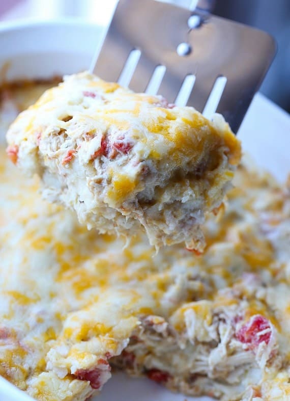 A slice of salsa verde chicken casserole is scooped out with a spatula.